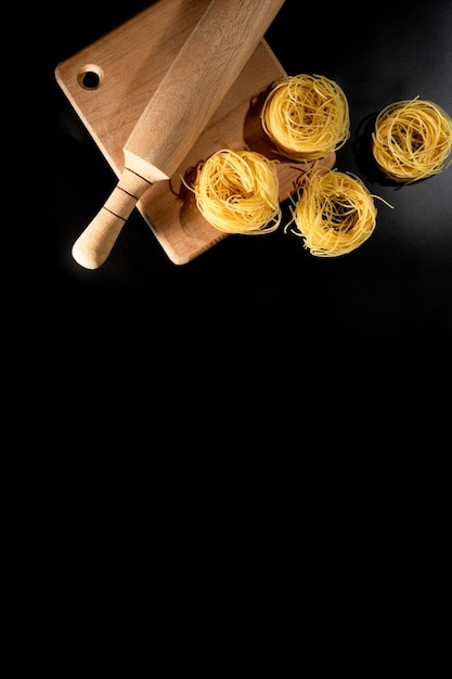 Rolled tagliatelle shape of italian pasta on black stone background High quality photo