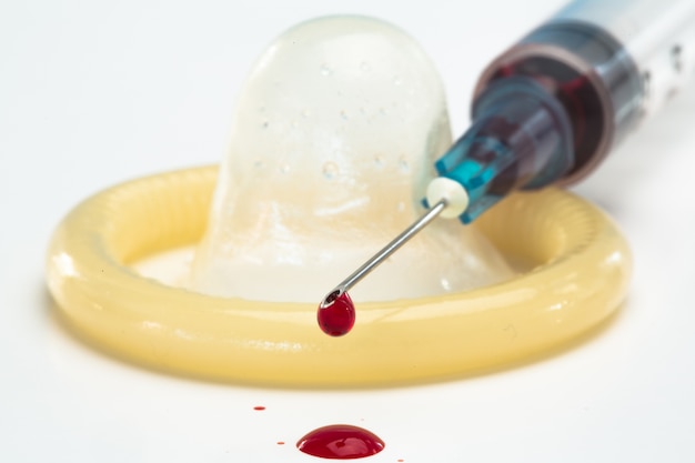 Photo rolled up condom and hypodermic needle dripping blood