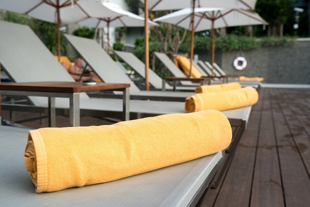 리조트 또는 호텔에서 수영장의 일광욕 배경에 주황색 수건을 올리고.