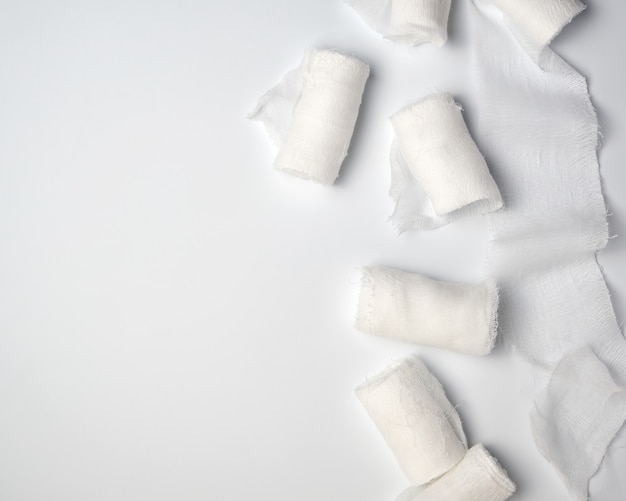 Rolled up white sterile medical bandages on a white background