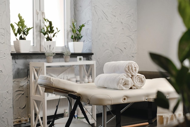 Foto asciugamani bianchi arrotolati sul tavolo da massaggio in un salone vuoto all'interno di una clinica estetica nessuno moderno