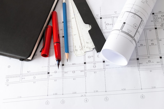 Rollen architectuurblauwdrukken en huisplannen op tafel en tekengereedschappen voor architecten.