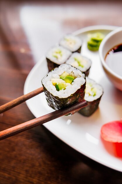 Rollen in nori zeewier met avocado, gepekelde gember en sojasaus. Aziatische keuken, traditionele schotel - sushi.