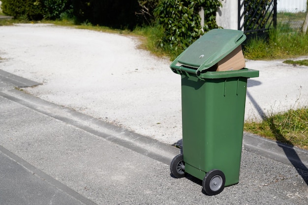 Rollende groene vuilnisbak overvolle zak wheelie in straat weg stad