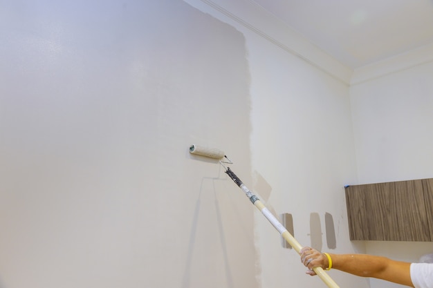 Photo roller brush painting close up details of painting walls, industrial worker using roller