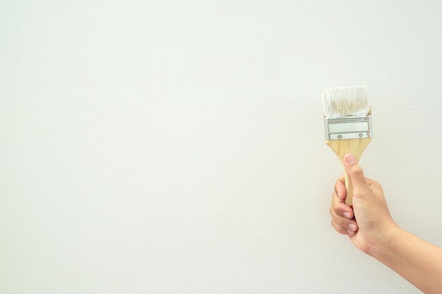 Foto pittura a pennello a rulli pittura da operaio sulla parete di superficie pittura di appartamento ristrutturazione con vernice bianca lasciare spazio vuoto bianco per scrivere testo descrittivo accanto