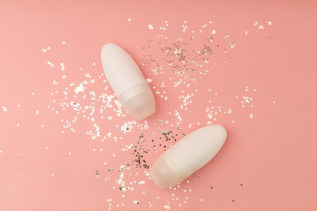 Roller deodorant in a white bottle on a pink background