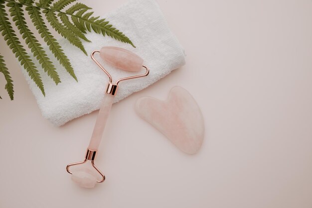 Roller and gua sha massage scraper with a fern leaf selfcare beauty and health concept