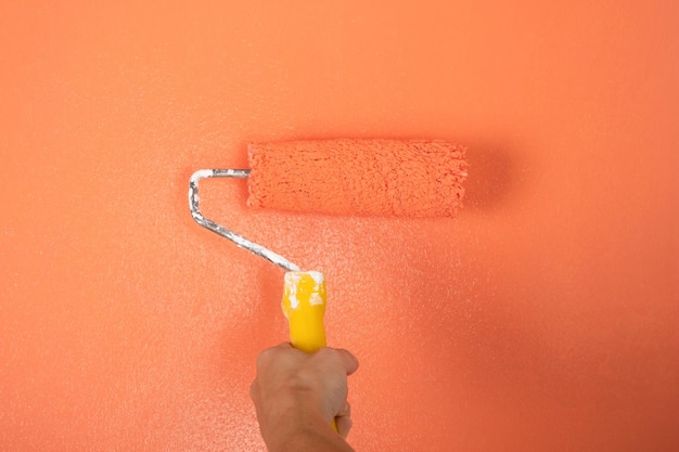 Roller for painting walls on the background of a peach wall