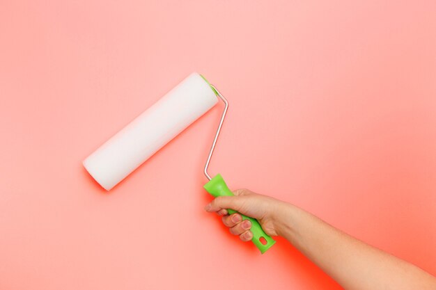 the roller on the pink wall. Painting walls