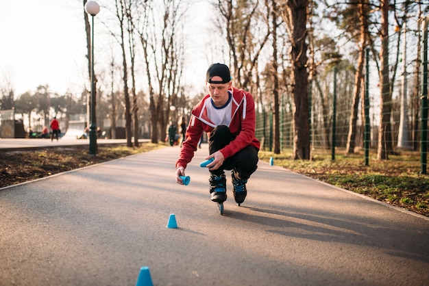 ローラースケートでスケートをする人、都市公園の歩道でバランス運動。男性のローラースケーターレジャー