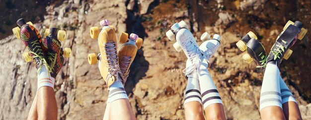 Photo roller skates fun and adventure travel with friends group lifting legs and showing off retro skating footwear while outside group of women enjoying hobby freedom and activity on holiday together