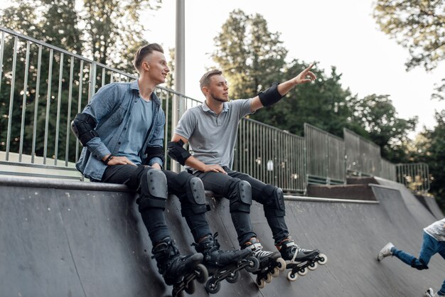 Roller skating, two skaters sitting on the ramp