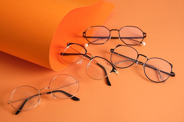 Rolles orange paper and several pairs of stylish glasses eyeglass frames in fashion trend bright colors