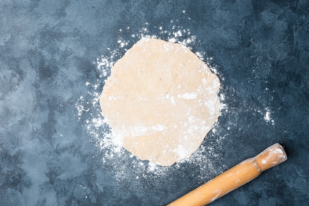 Rolling dough on a table with a wooden rolling pin. 