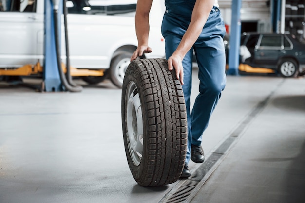 Rolling on the floor. Employee in the blue colored uniform works in the automobile salon