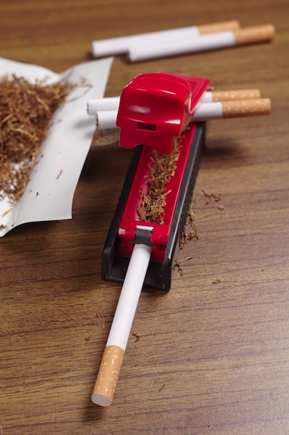 Rolling machine, cigarettes and tobacco on table