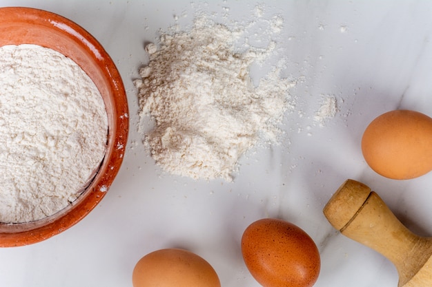 Rolling pin, cup of flour and eggs