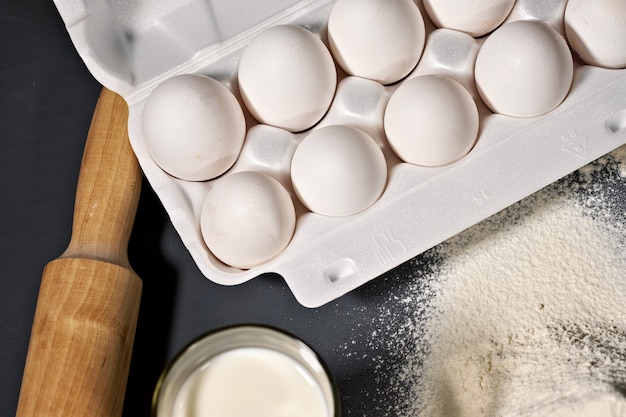 Rolling pin, eggs, flour on grey background, selective focus