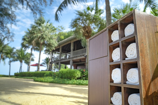 Photo rolling towel in the wooden square box in the private hotel beach garden, prepared for traveler to use.