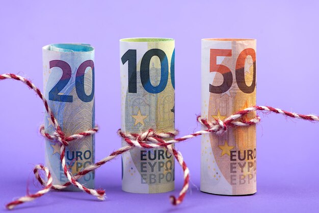 Rolls of 100 50 and 20 euro money banknotes isolated on light purple background depth of field