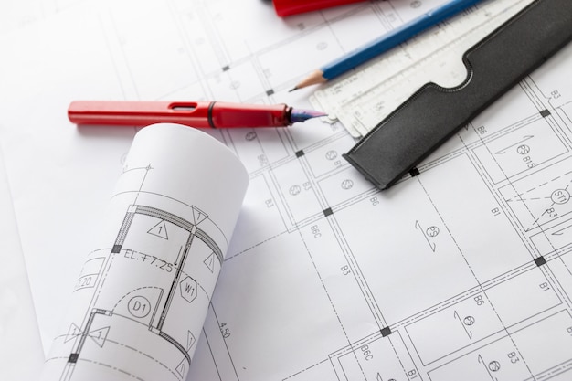 テーブル上の建築設計図と家の計画のロールと建築家の描画ツール。