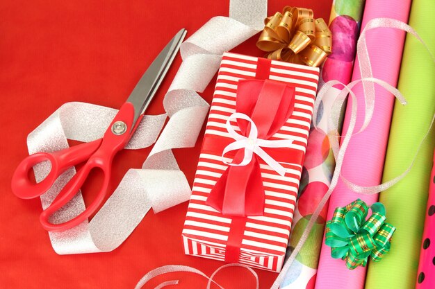 Foto rotoli di carta da regalo natalizia con nastri, fiocchi su sfondo colorato
