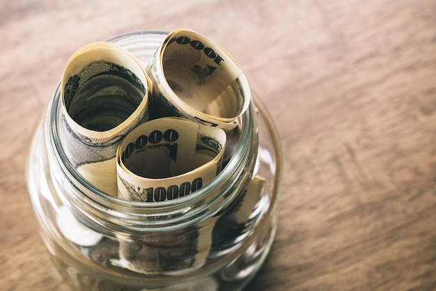 Rolls of Japanese yen money banknotes in the glass jar