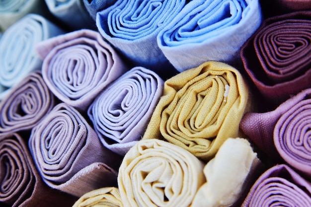 Rolls of multicolored fabrics close-up.