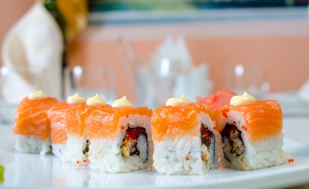 Rolls, sushi and ginger on a white plate and a light surface.