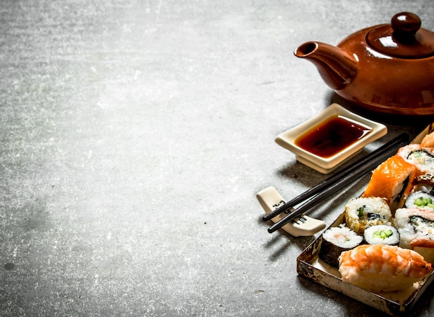 The rolls and sushi, herbal tea and soy sauce. On the stone table.