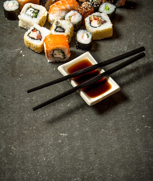 The rolls and sushi with soy sauce. On the stone table.