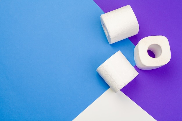 Rolls of unfolded toilet paper on a blue background. Flat lay, top view