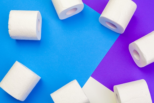 Rolls of unfolded toilet paper on a blue background. Flat lay, top view