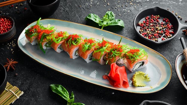 Rolls with salmon caviar and chuka salad on a plate Sushi Top view Rustic style