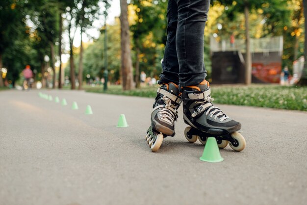 Rolschaatsen, mannelijke schaatser die rond de kegels in het park rolt. Rolschaatsen in de stad, actieve extreme sporten buitenshuis, vrije tijd voor jongeren, rolschaatsen