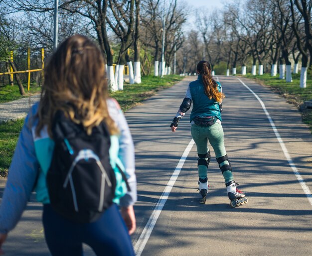 Rolschaatsen met twee jonge en mooie meisjes. Uitzicht vanuit de eerste persoon.