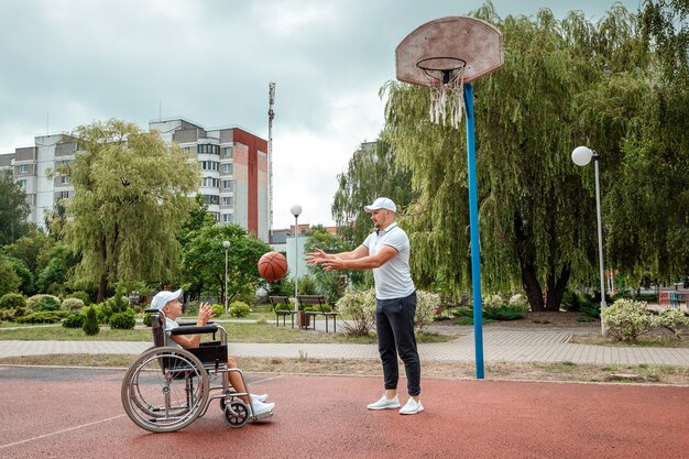 Rolstoelconcept, gehandicapt kind, vader en zoon, vol leven, verlamd. Een gehandicapte zoon in een rolstoel speelt met zijn vader op straat, tijd met zijn gezin.