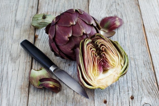 Foto carciofi romani su una tavola di legno con coltello