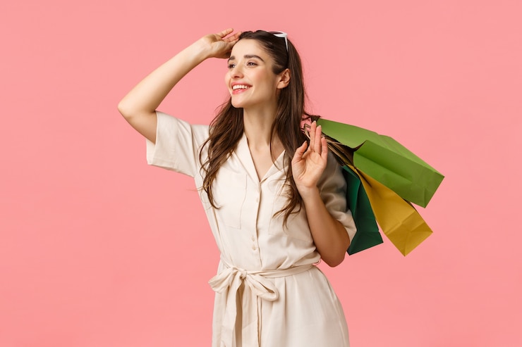 Photo romance, shopaholic and women concept. cheerful tender feminine woman holding shopping bags behind back, taking-off glasses and smiling happily left, enjoy browsing stores