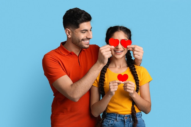 Romantic arab couple holding red paper hearts and having fun together