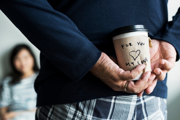 L'uomo asiatico romantico porta una tazza di caffè per la moglie