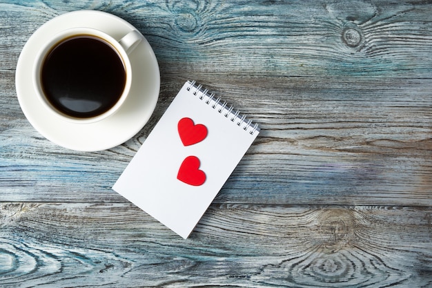 Romantic background with a Cup of coffee and two hearts on a Notepad on a wooden gray-blue