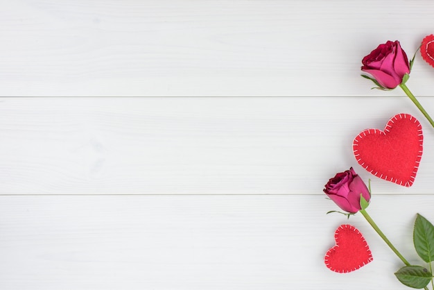 Photo romantic background with roses and hearts on a white wooden table. top view, copy space.