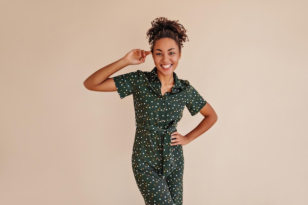 Romantic black girl posing with hand on hip Studio shot of glamorous african american woman in green overalls