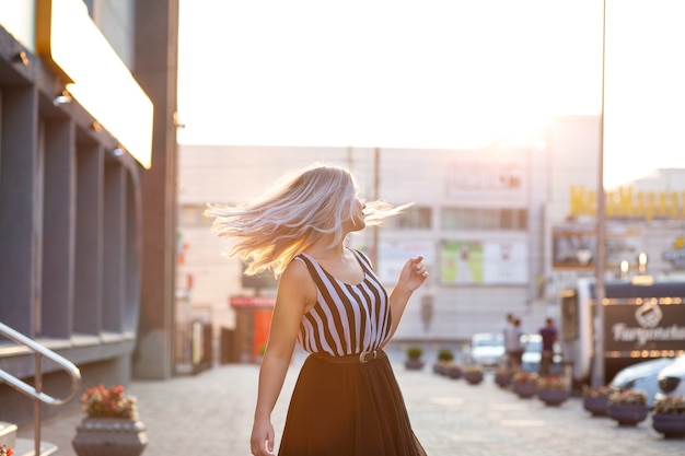 Romantic blonde model with fluttering hair posing with evening light. Space for text