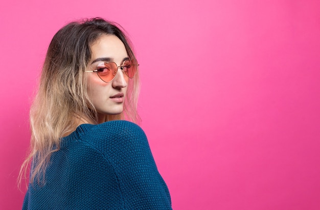 Romantic blondehaired girl in trendy heart glasses posing with shy smile