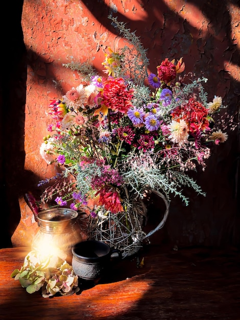 Romantic bouquet with flowers of dahlia chrysanthemum perennial aster montbrecia geyhera wormwood flowers and sedum with cezve and coffee cup in sunlight on old rusty background