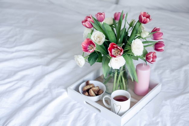 Romantic breakfast in bed. Bouquet of flowers. Roses and tulips. 