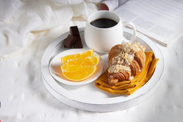 Romantic breakfast morning coffee in bed oranges and croissants on a white wooden tray